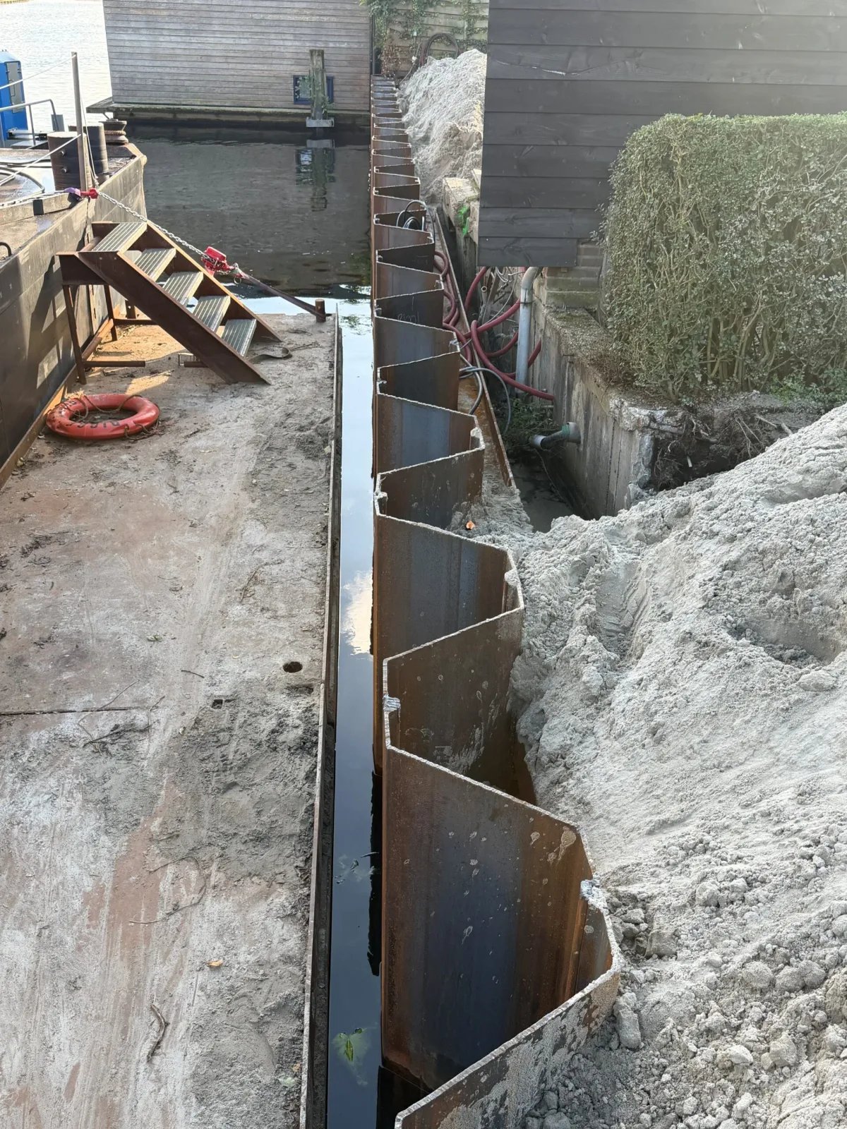 Smalle ruimte tussen de nieuwe damwand en de bestaande betonnen kade in Baarn