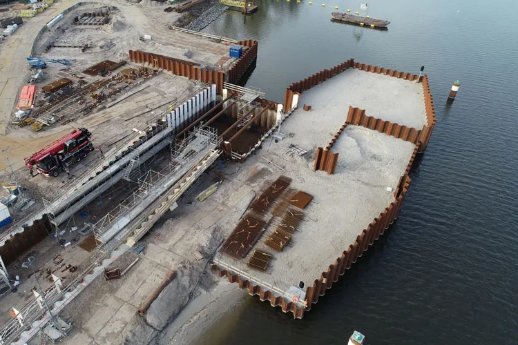 Luchtfoto van een waterbouwproject met stalen damwanden rond een bouwkuip in het water